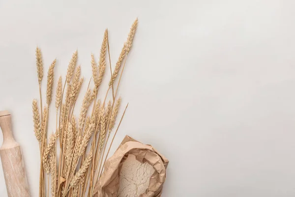 Vista superior de espigas de trigo, rodillo y paquete de harina aislados en blanco - foto de stock