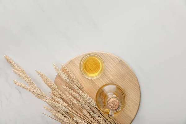 Vista superior de la tabla de cortar redonda con espigas y aceite en la superficie de mármol — Stock Photo