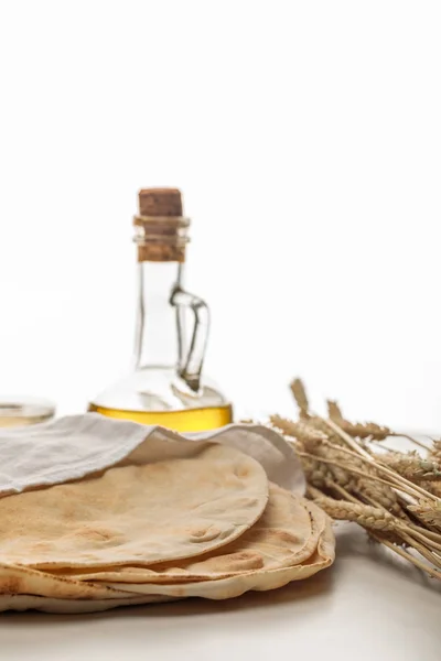 Pão lavash coberto com toalha branca perto de espigas e óleo isolado em branco — Fotografia de Stock