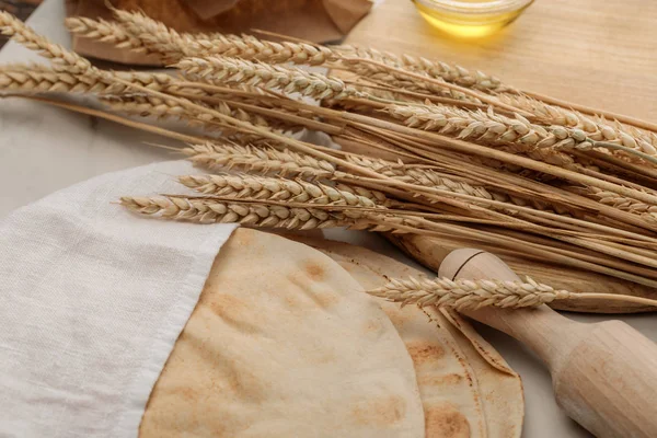 Lavash bread covered with white towel near rolling pin and cutting board with spikes and oil on marble surface — Stock Photo