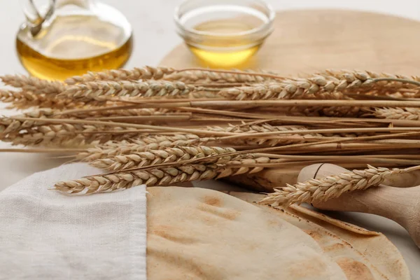 Lavash bread covered with white towel near rolling pin and cutting board with spikes and olive oil — Stock Photo