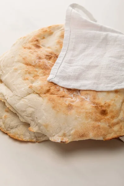 Pan de lavash cubierto con toalla en la superficie blanca - foto de stock