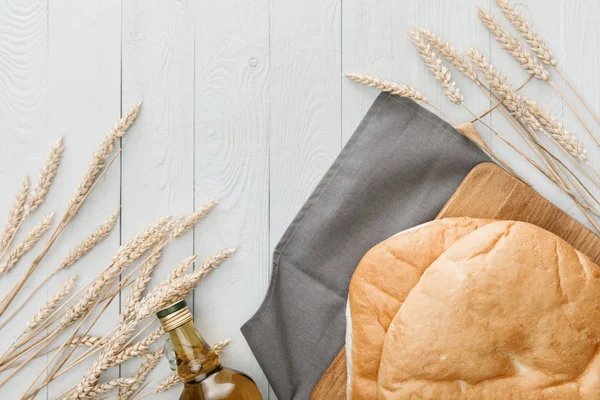 Vue du dessus du pain de lavande sur une serviette grise près des pointes et de l'huile d'olive sur une surface en bois blanc — Photo de stock