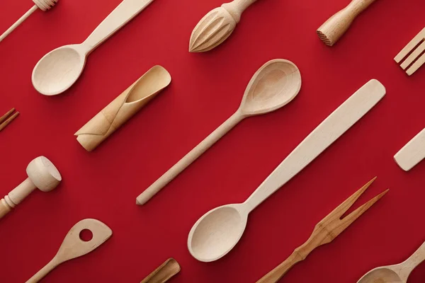 Top view of natural wooden spoons, fork and kitchenware on red background — Stock Photo