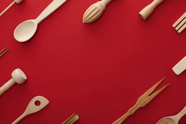 Vista superior de cucharas de madera natural, tenedor y utensilios de cocina sobre fondo rojo con espacio para copiar — Stock Photo