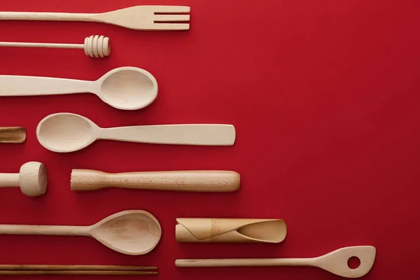 Top view of natural wooden spoons and kitchenware on red background with copy space — Stock Photo