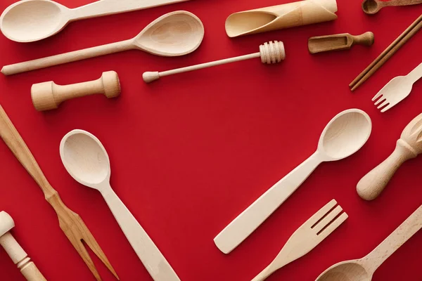 Верхний вид ложки, вилки, палочки для еды и кухонные принадлежности на красном фоне с копировальным пространством — стоковое фото