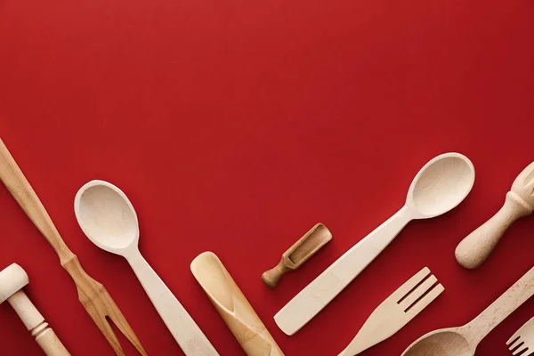 Vue de dessus des cuillères, fourchettes, baguettes et ustensiles de cuisine en woden sur fond rouge avec espace de copie — Photo de stock