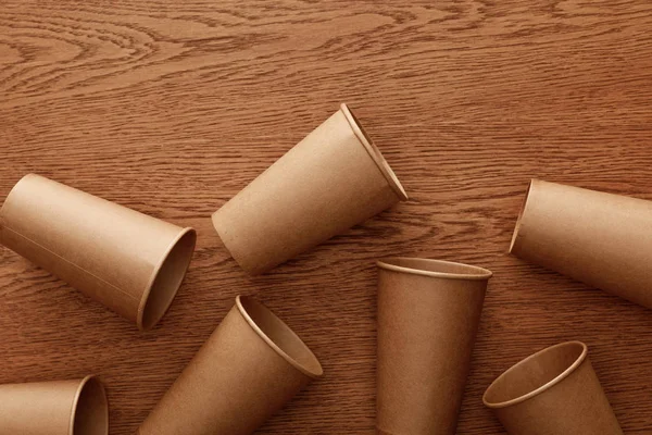 Vista superior de vasos de papel vacíos sobre fondo de madera marrón - foto de stock