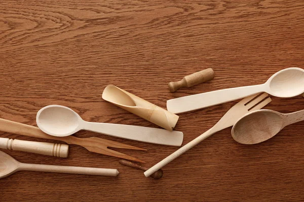 Vista superior de cubiertos de madera y utensilios de cocina sobre fondo marrón - foto de stock