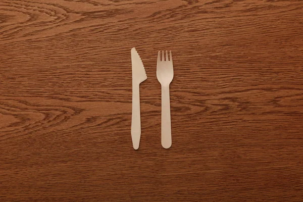 Vista dall'alto di forchetta e coltello in legno su sfondo marrone — Foto stock