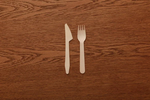 Top view of wooden fork and knife on brown background — Stock Photo