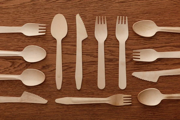 Top view of wooden spoons forks and knifes on brown background — Stock Photo