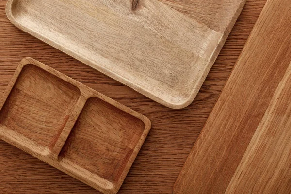 Vista superior de platos de madera y tabla de cortar sobre fondo marrón — Stock Photo