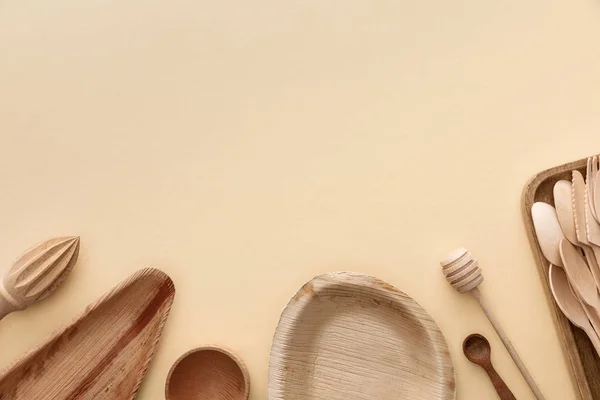 Вид зверху на дерев'яні тарілки, ложки і ручний соковижималка на бежевому фоні — стокове фото