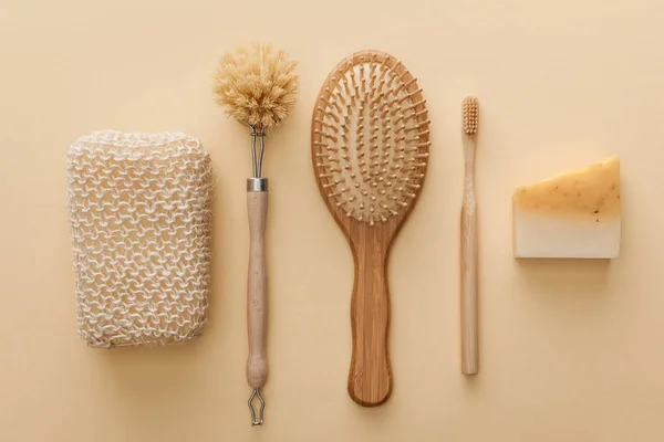 Vue de dessus de l'éponge de bain naturelle près de brosse à dents, brosse à cheveux, brosse à corps et savon sur fond beige — Photo de stock