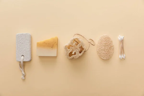 Vista superior de jabón natural cerca de hisopos de algodón, esponja y piedra pómez sobre fondo beige - foto de stock