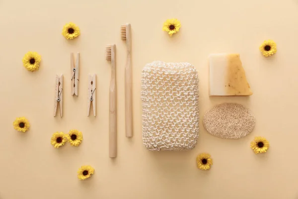 Vue de dessus des pinces à linge en bois, brosses à dents, éponge de bain, savon naturel et loofah sur fond beige avec des fleurs — Photo de stock