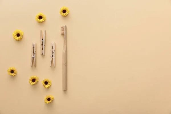 Vista superior de pinzas de madera y cepillo de dientes sobre fondo beige con flores - foto de stock