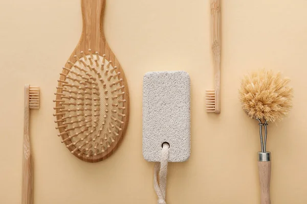 Top view of toothbrushes, hairbrush, body brush and pumice stone on beige background — Stock Photo