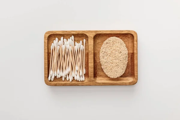 Top view of wooden dish with cotton swabs and loofah on white background — Stock Photo
