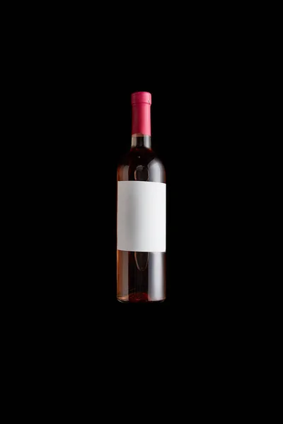 Top view of bottle with rose wine and blank white label isolated on black — Stock Photo