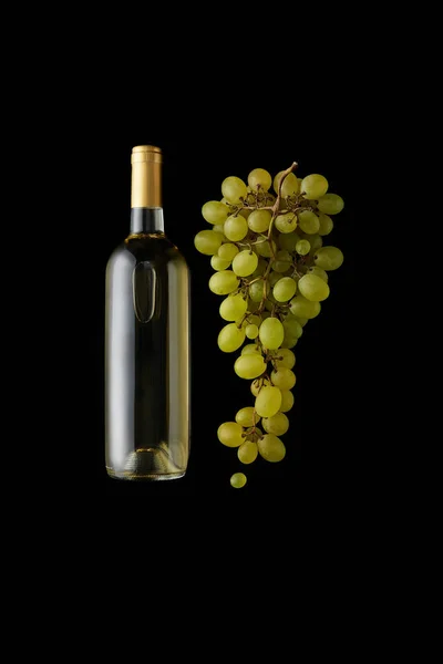 Вид зверху пляшки білого вина біля стиглого зеленого винограду ізольовано на чорному — стокове фото