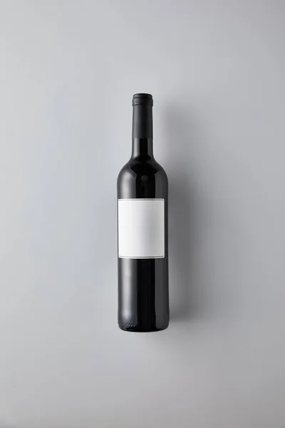 Vue du dessus de la bouteille avec vin rouge et étiquette vierge sur fond blanc — Photo de stock