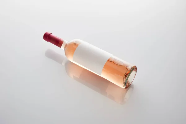 Garrafa com vinho rosa e rótulo em branco no fundo branco — Fotografia de Stock