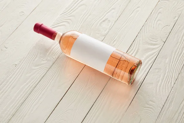 Flasche mit Rosenwein und leerem Etikett auf weißer Holzoberfläche — Stockfoto