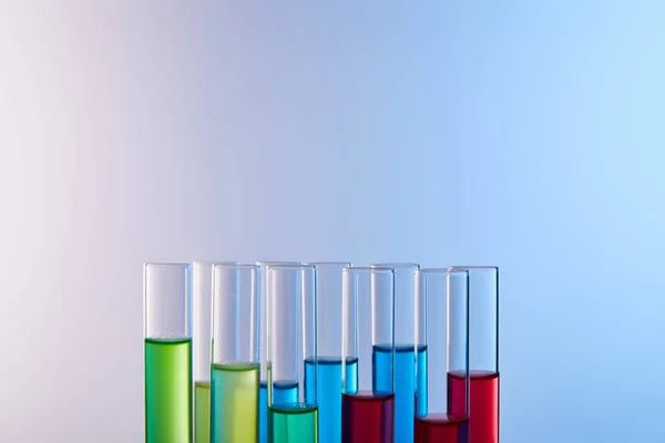 Glass test tubes with colorful liquid on blue background — Stock Photo