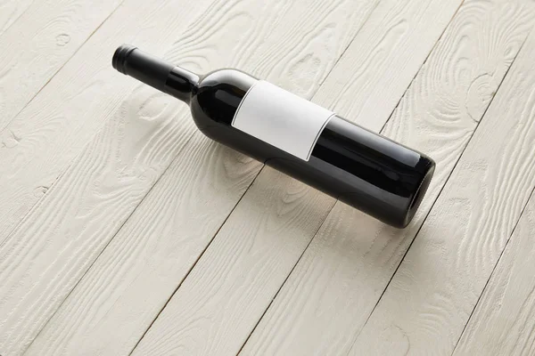 Bottles with wine and blank label on white wooden surface — Stock Photo