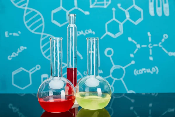 Tubo de ensayo de vidrio y frascos con líquido colorido sobre fondo azul con estructura molecular - foto de stock