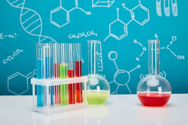 Reagenzgläser und Kolben mit bunter Flüssigkeit auf blauem Hintergrund mit molekularer Struktur — Stockfoto