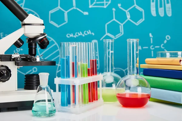 Mikroskop, Bücher, Glas-Reagenzgläser und Kolben mit bunter Flüssigkeit auf blauem Hintergrund mit molekularer Struktur — Stockfoto
