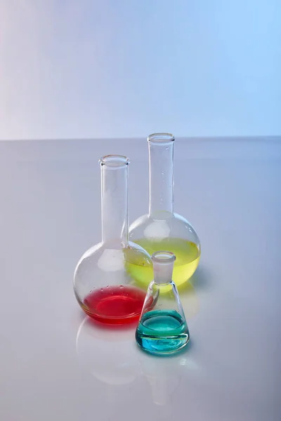 Flacons en verre avec liquide jaune, bleu et rouge coloré — Photo de stock