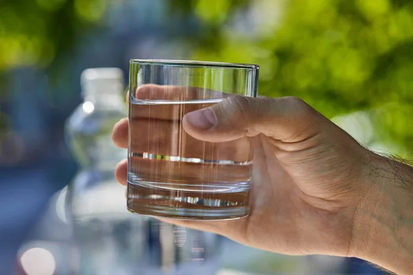 Vue recadrée de l'homme tenant le verre avec de l'eau douce claire extérieure — Photo de stock