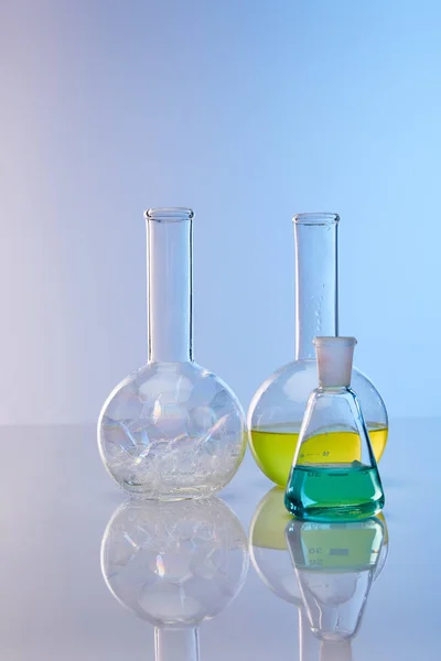 Glass flasks with colorful yellow, blue liquid and bubbles — Stock Photo