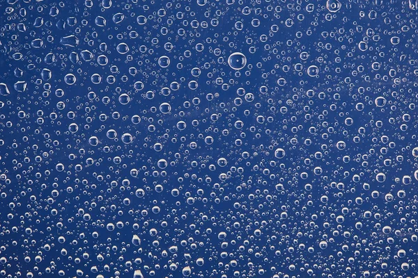 Klare transparente Wassertropfen auf blauem Hintergrund — Stockfoto