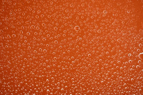 Gotas de água transparentes claras no fundo laranja — Fotografia de Stock