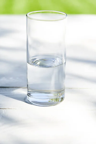 Eau fraîche et propre en verre transparent à la journée ensoleillée sur table en bois — Photo de stock