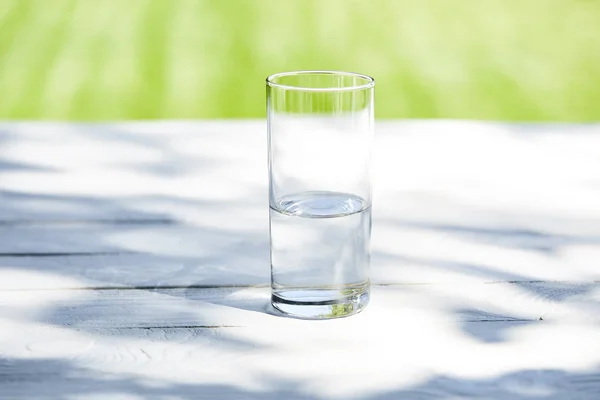 Fresh clean water in transparent glass at sunny day on wooden table — Stock Photo