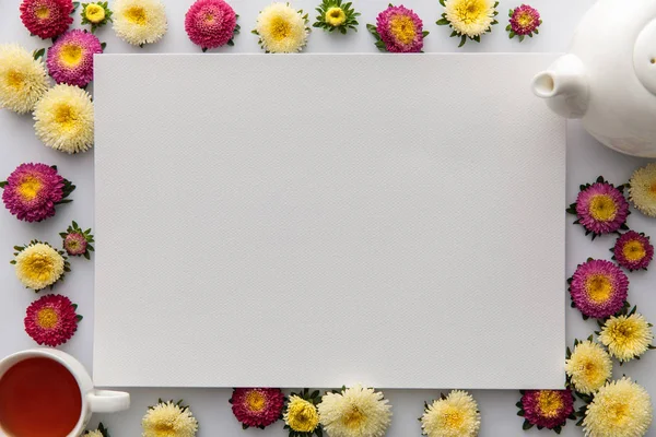 Draufsicht auf gelbe und lila Astern und leeres Papier auf weißem Hintergrund — Stockfoto