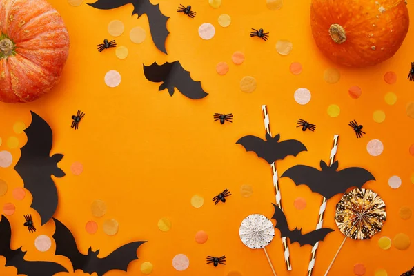 Top view of pumpkin, bats and spiders with confetti on orange background, Halloween decoration — Stock Photo