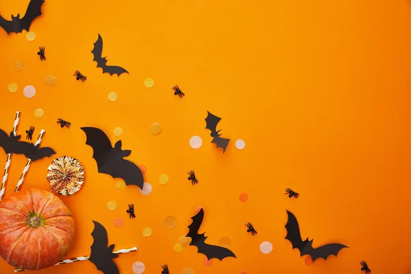 Top view of pumpkin, bats and spiders with confetti on orange background, Halloween decoration — Stock Photo