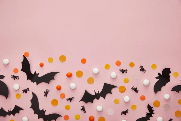 Vista superior de murciélagos y arañas con confeti sobre fondo rosa, decoración de Halloween - foto de stock