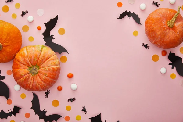 Draufsicht auf Kürbis, Fledermäuse und Spinnen mit Konfetti auf rosa Hintergrund, Halloween-Dekoration — Stockfoto