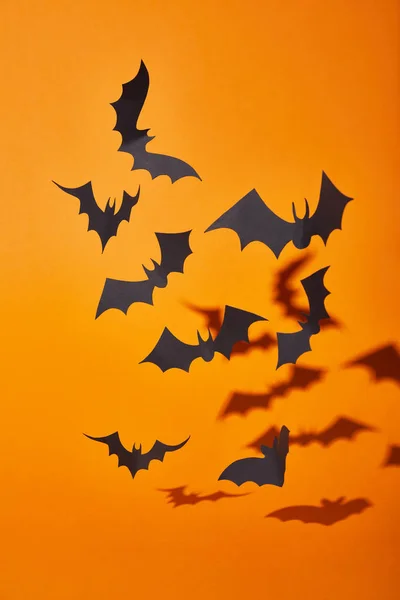 Murciélagos de papel con sombra sobre fondo naranja, decoración de Halloween - foto de stock