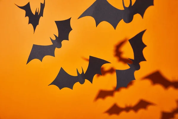 Murciélagos de papel con sombra sobre fondo naranja, decoración de Halloween - foto de stock