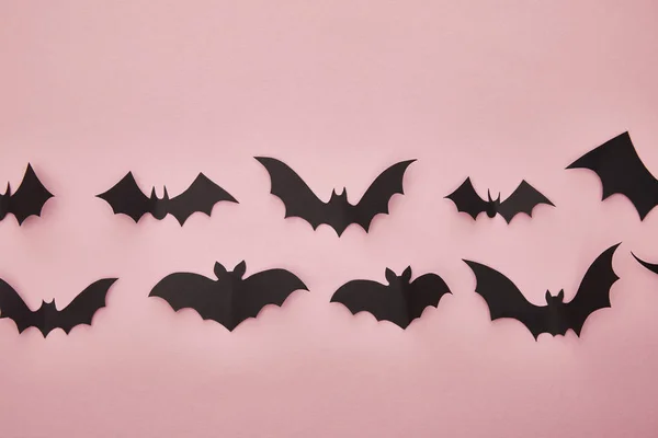 Vista superior de morcegos de papel preto no fundo rosa, decoração de Halloween — Fotografia de Stock